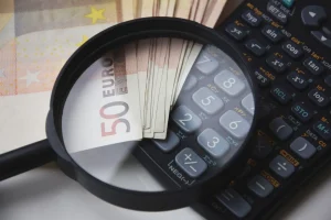Magnifying glass zooming in on Euro banknotes and a scientific calculator